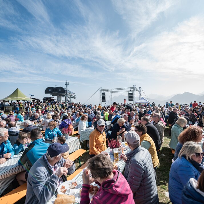 Menschen sitzen dicht gedrängt an langen Tischen und genießen Speisen bei einer gut besuchten Freiluftveranstaltung. | © Gianvito Coco