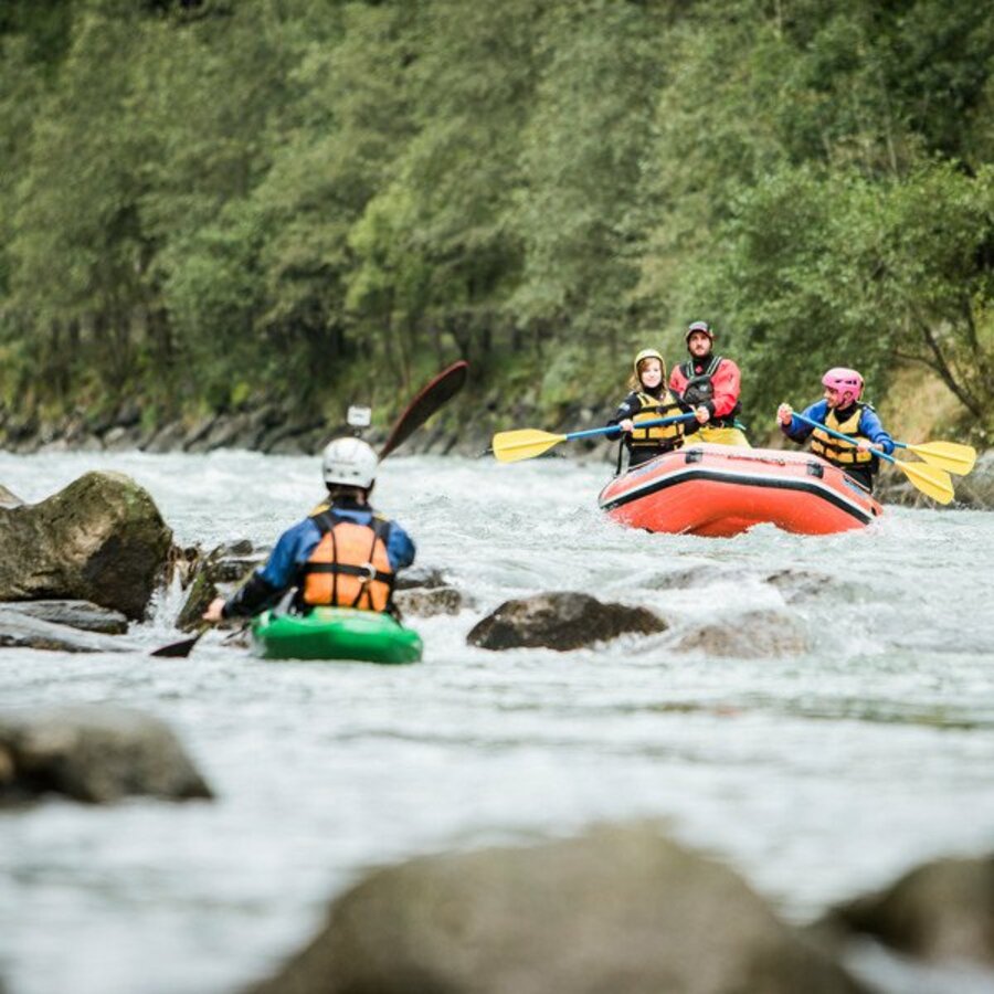 Eine Gruppe auf einem Rafting-Boot und ein Kayak-Fahrer auf einem Fluss. | © IDM Südtirol