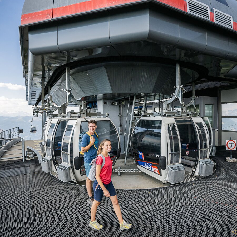 Eine Frau und ein Mann beim Ein- und Ausstieg der Aufstiegsanlage Kronplatz 2000 im Sommer. | © Harald Wisthaler