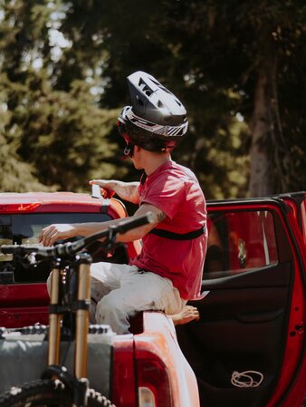 Ein Mountainbiker sitzt mit seinem Bike in der Ladefläche eines roten Pick-Ups. | © Daniel Niederkofler