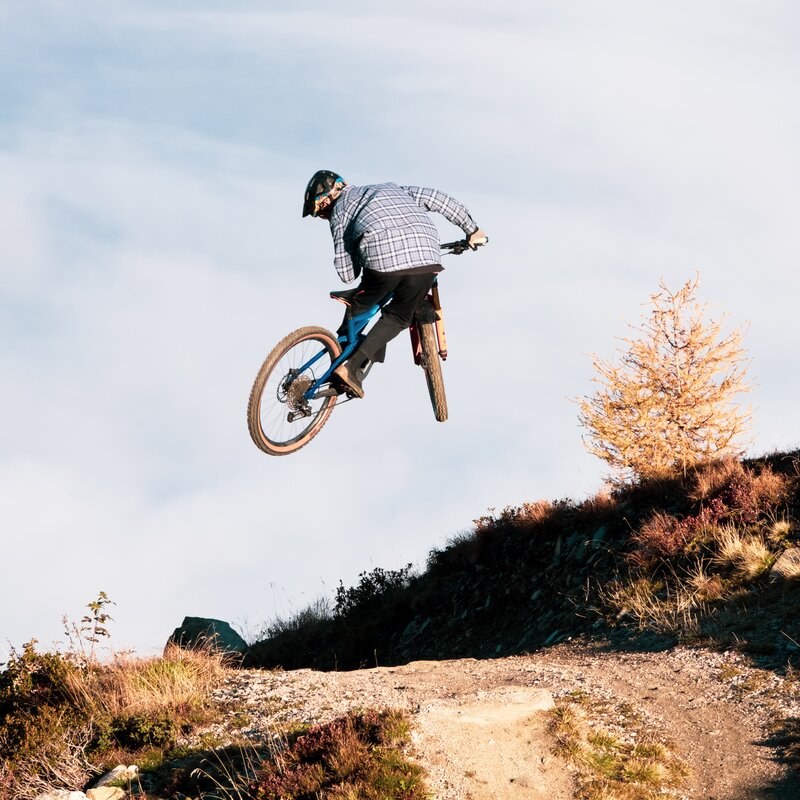 Ein Mountainbiker performt einen Sprung auf einem Bergweg. | © Daniel Niederkofler