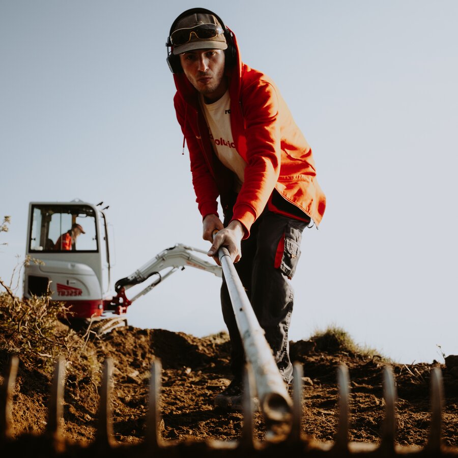 Eine Person mit Schutzbrille und roter Jacke schiebt ein Arbeitsgerät über frischen Boden. | © Daniel Niederkofler