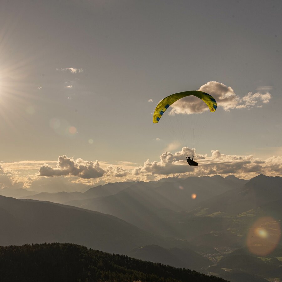 Ein Paragleiter über dem Kronplatz bei Sonnenuntergang. | © Skirama Kronplatz