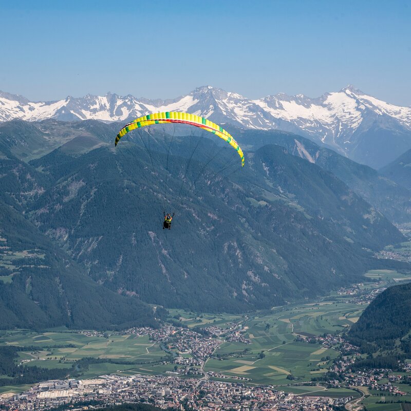 Ein Paragleiter schwebt über dem Brunecker Talkessel. | © Skirama Kronplatz