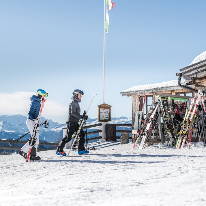 Zwei Skifahrer mit ihren Skiern in der Hand auf den Weg zu einer Hütte. | © Harald Wisthaler