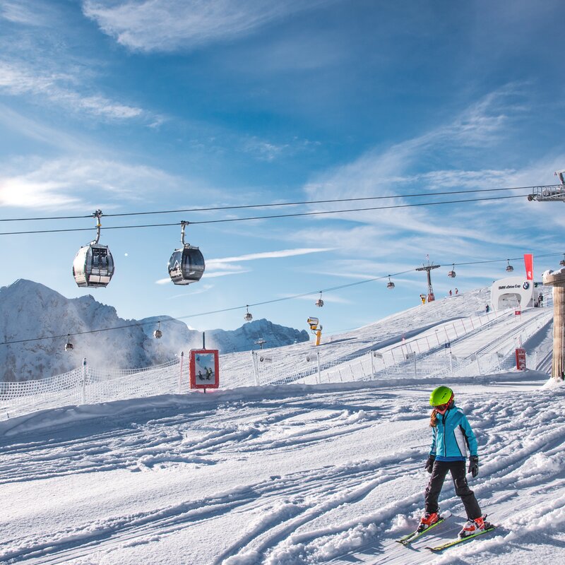 Kinder fahren mit dem Skilehrer im Kids Safety Park bei blauem Himmel. | © Skirama Kronplatz