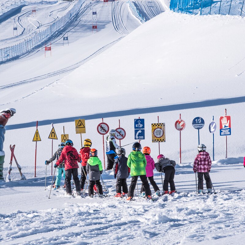 Kinder fahren mit dem Skilehrer im Kids Safety Park bei blauem Himmel. | © Skirama Kronplatz