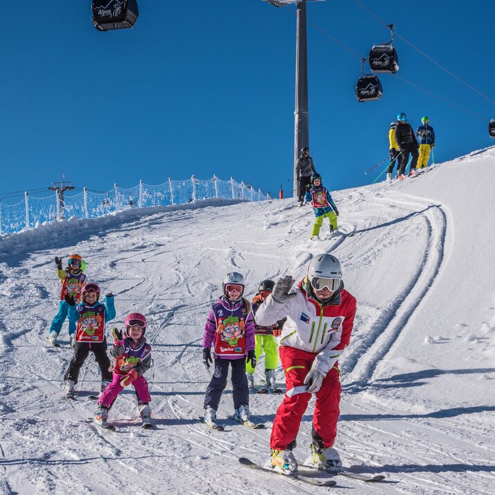 Kinder fahren mit dem Skilehrer im Kids Safety Park bei blauem Himmel. | © Skirama Kronplatz