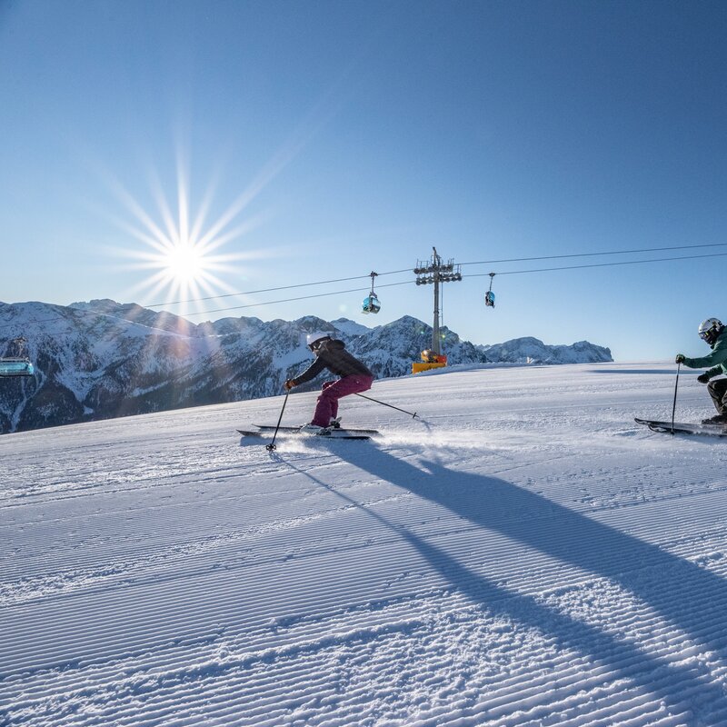 Zwei Skifahrer auf den Pisten vom Kronplatz bei blauem Himmel. | © Skirama Kronplatz
