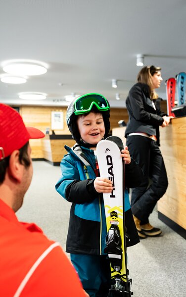 Ein Kind wird von einem Mitarbeiter des Skidepots beraten. | © Skiarea Miara