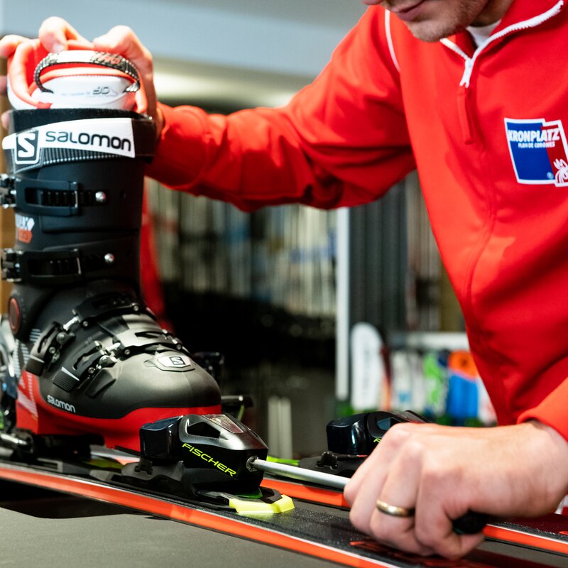 Ein Mitarbeiter des Skiverleihes passt den Skischuh an den Ski an. | © Skiarea Miara