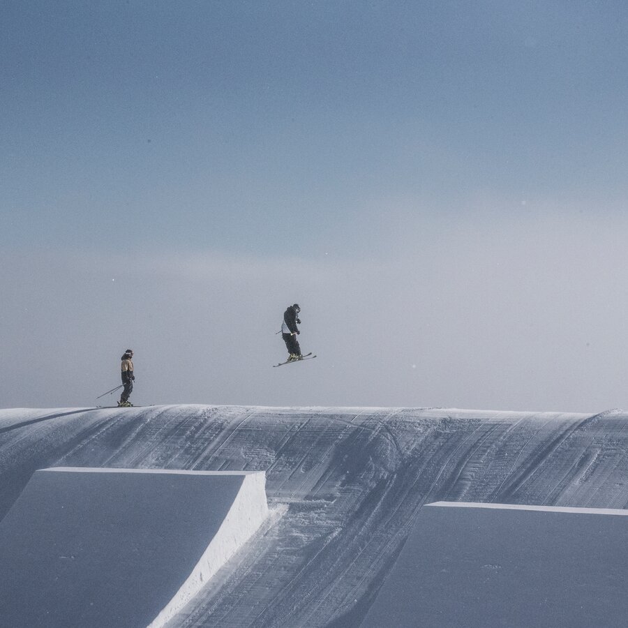 Zwei Snowboarder im Snowpark Kronplatz bei blauem Himmel. | © Skirama Kronplatz