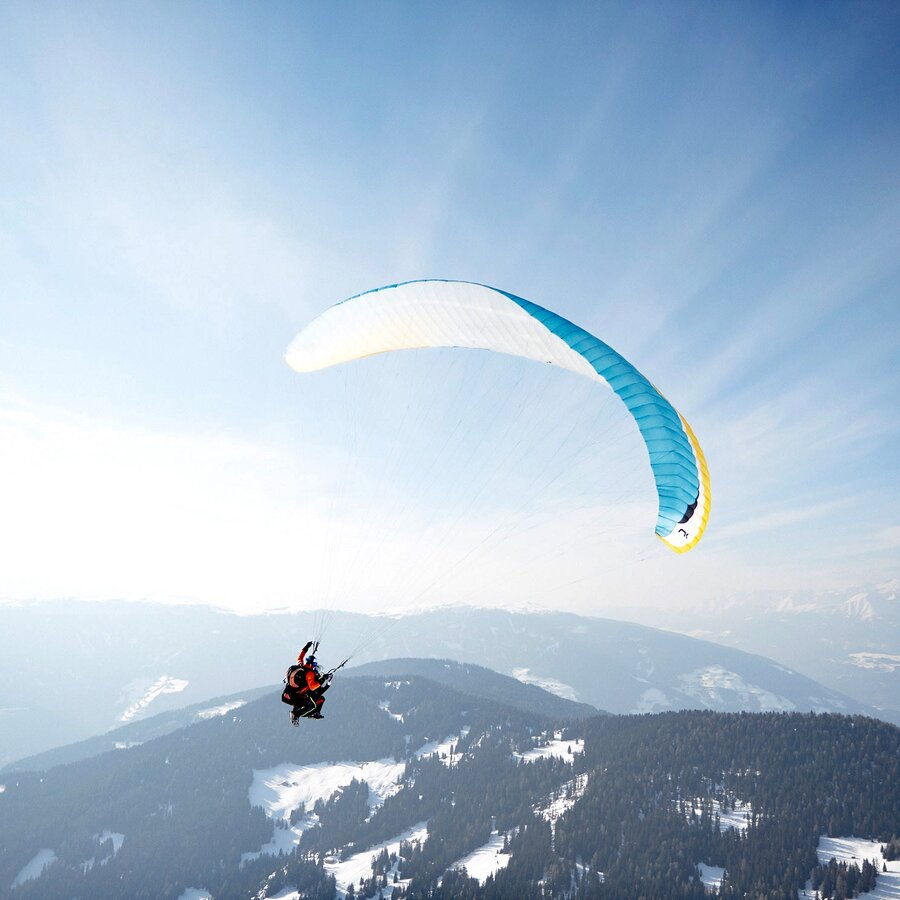 Ein Paragleiter im Winter oberhalb des Kronplatz-Gipfels. | © Tandemflights Kronplatz