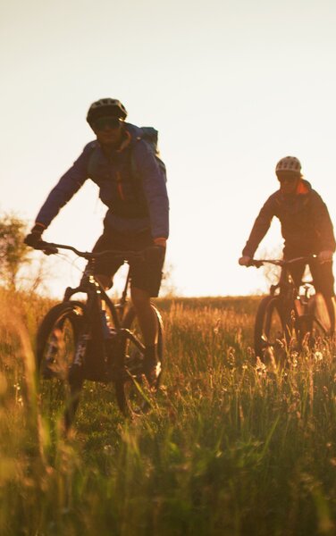 Uomini in bicicletta attraversano i campi | © TV Olang